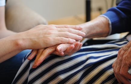 Jüngere Person hält Hände einer älteren Person