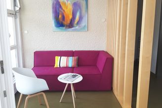 Magenta Sofa mit gestreiftem Kissen und Tisch vor abstraktem Gemälde