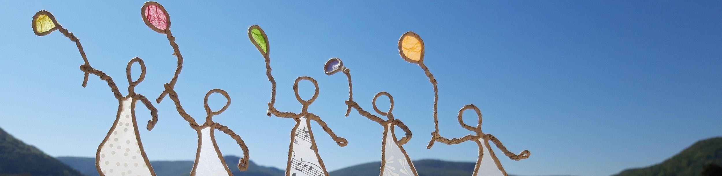 Fünf stilisierte Figuren aus Draht und Papier mit bunten Ballons