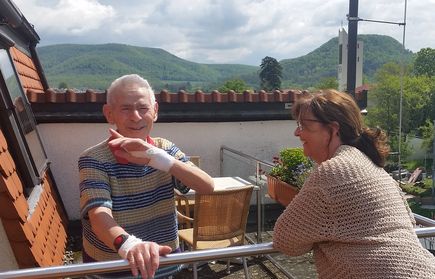 Älterer Mann mit Verband an der Hand und Frau auf Balkon