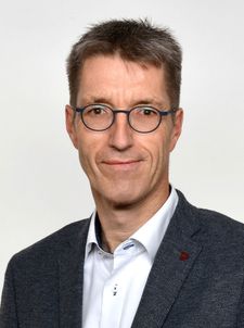 Porträt eines Mannes mit runder Brille und Sakko