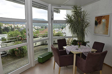 Essbereich mit Tisch und vier Stühlen vor verglaster Balkontür